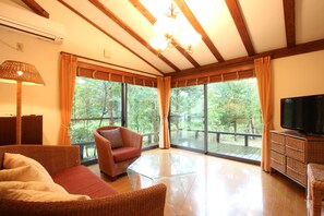 A spacious living area with a large window, a television, wicker furniture, and a glass coffee table. - Auberge - A Ma Façon - (Kokonoe)