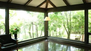 Una habitación con ventanas amplias, piso de madera y una lámpara.