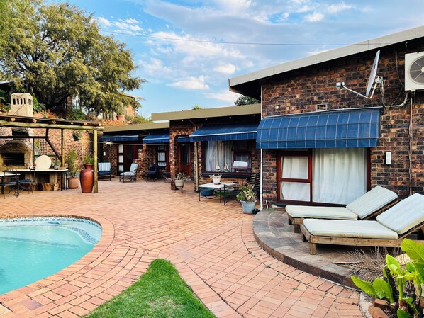 Relax by the pool surrounded by lush greenery and comfortable seating options.
