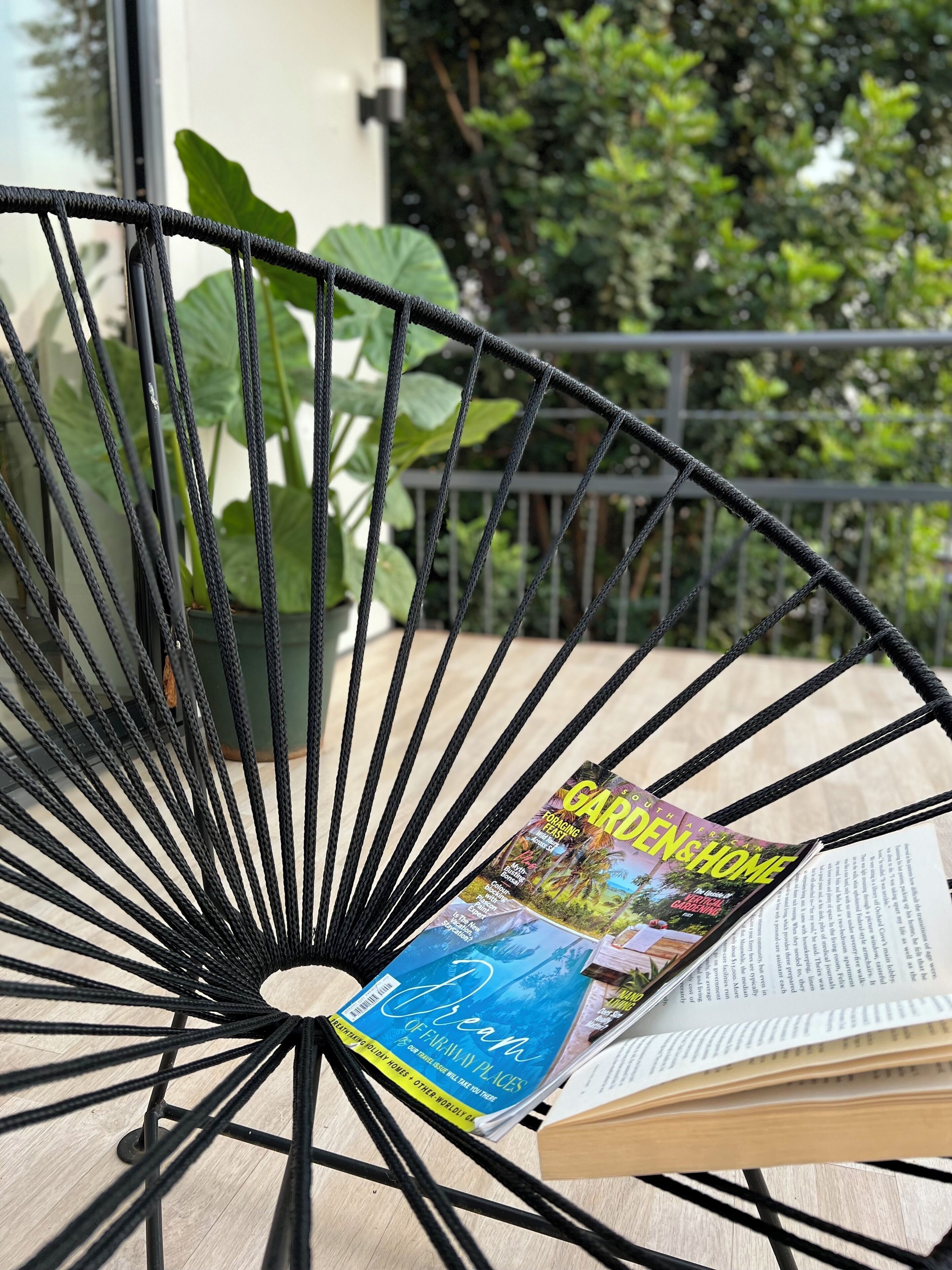 A black metal chair with a book titled "Dreams of February Places" and a magazine on it.