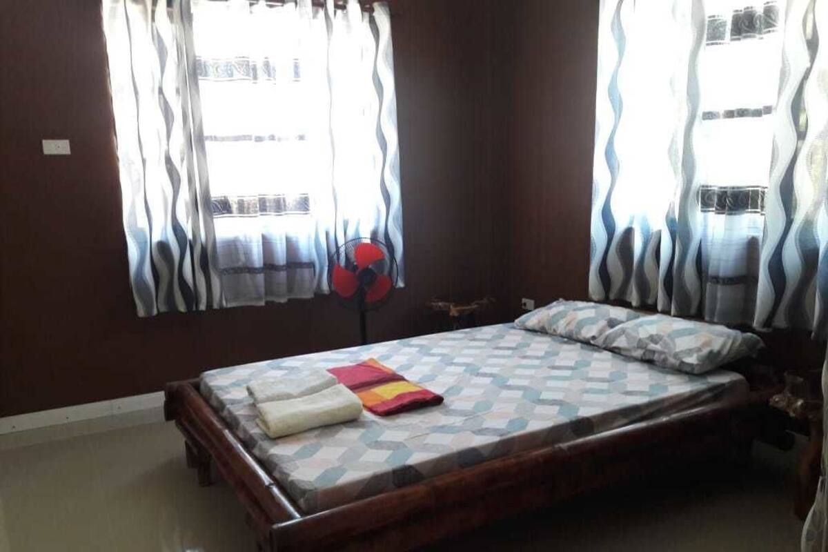 A bedroom with a bed, curtains, and a fan.