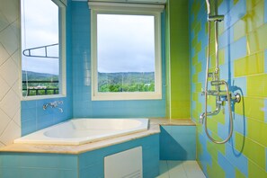 A bathroom with a bathtub, a window, and a shower.