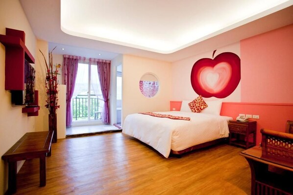 A bedroom with a large bed, a wooden bench, a small table, a wall-mounted TV, and a balcony with curtains.