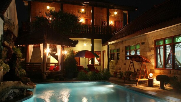 A pool area with a hot tub, outdoor seating, and a staircase leading to a balcony.