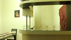 A modern dining area with a glass table, chairs, and a bar counter.