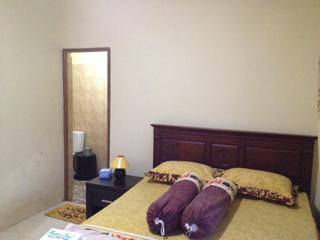 Una habitación de hotel con cama, mesita de noche, lámpara y espejo.