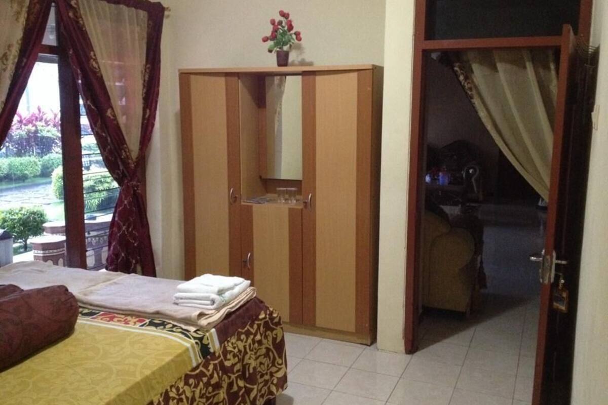 Un dormitorio con cama, armario y baño visible a través de una puerta abierta.