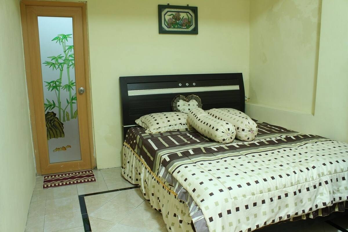 Un dormitorio con una cama, una puerta con diseño de bambú y un pequeño cuadro en la pared.