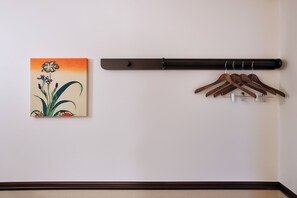 A wall-mounted coat rack with wooden hangers and a painting of flowers.