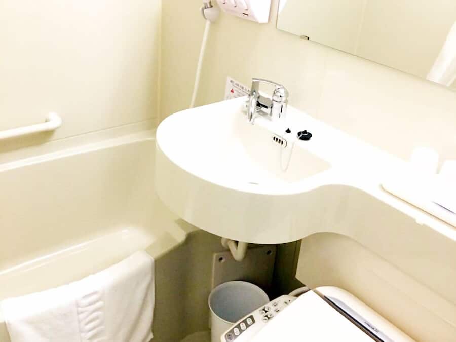 A bathroom with a white sink, a toilet, a bathtub, and a towel rack.
