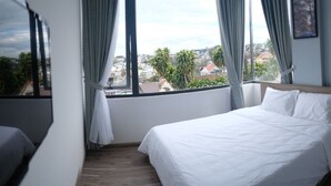 A hotel room with two beds, a view of the city through large windows, and a wooden floor. - Dalat Memory Inn (Xuan Huong - Da Lat)