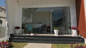 A modern building with a glass entrance, steps leading up to it, and potted plants on either side. - Dalat Memory Inn (Xuan Huong - Da Lat)