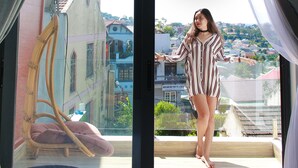 A room with a large window, a chair, and a view of buildings outside. - Dalat Memory Inn (Xuan Huong - Da Lat)