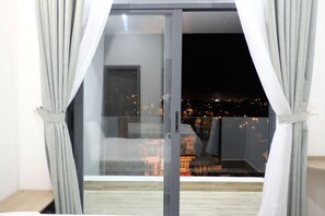 A room with a sliding glass door leading to a balcony with a city view at night. - Dalat Memory Inn (Xuan Huong - Da Lat)