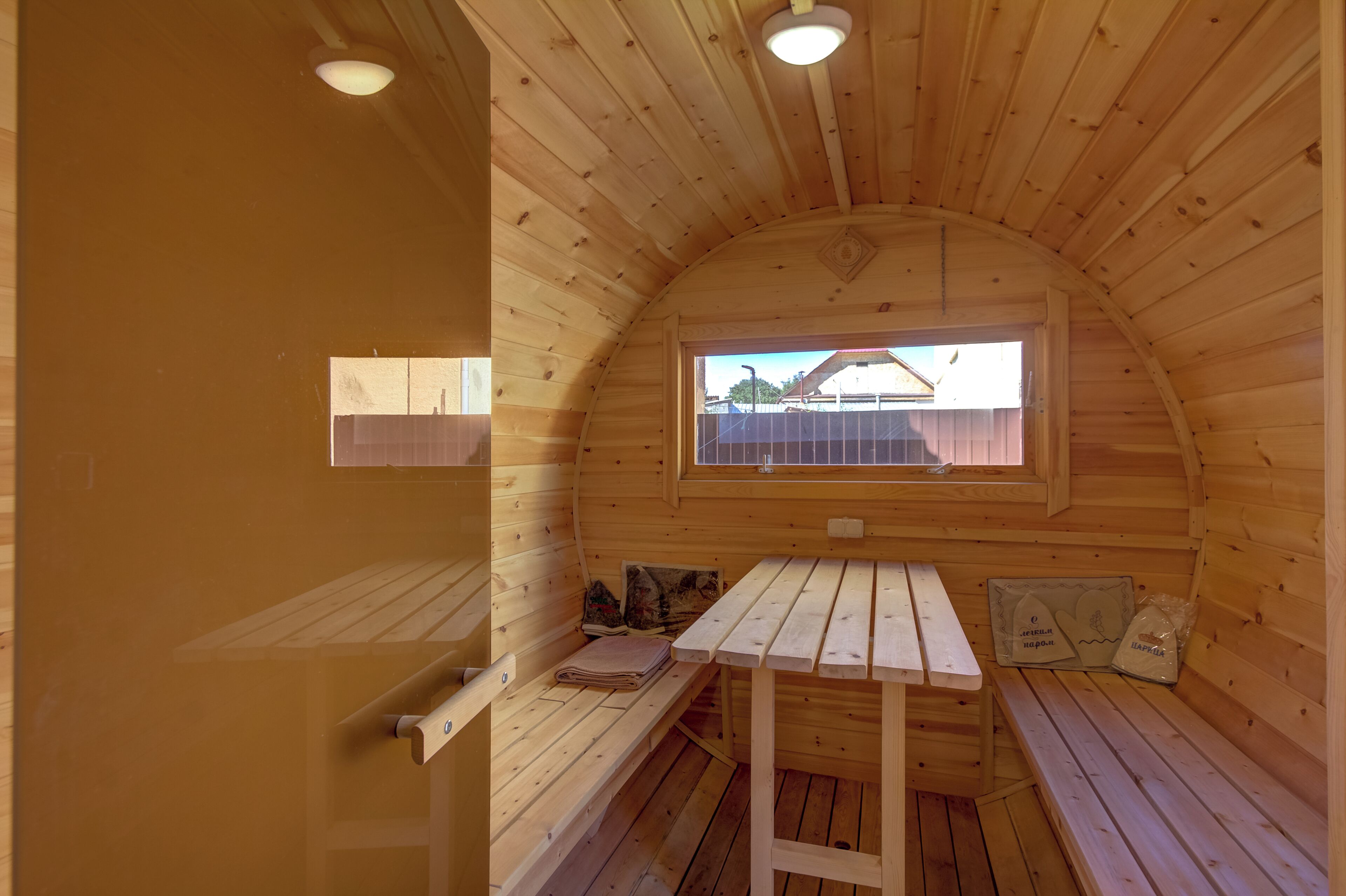 Una cabaña de madera acogedora con un banco, una mesa y un ventanal con vista a un área cercada.