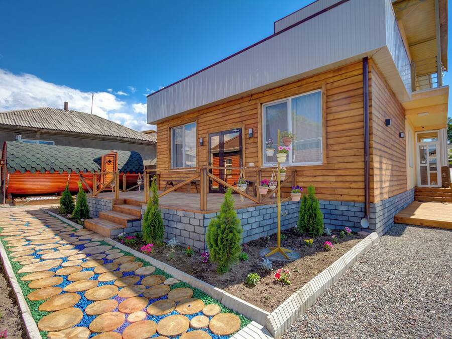 A modern house with a wooden exterior, a stone pathway, and small potted plants.