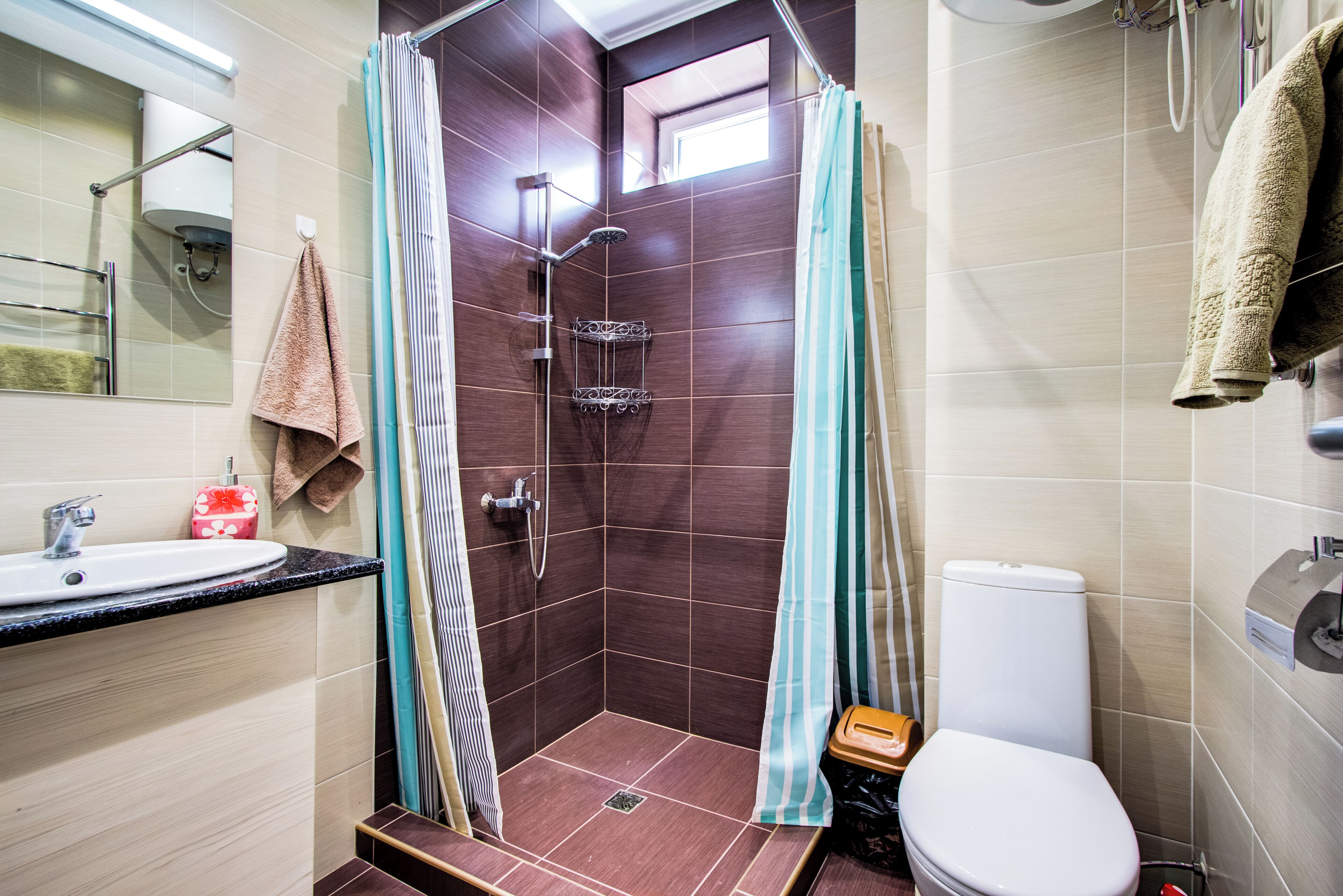 Baño con ducha, inodoro, lavabo y ventana.