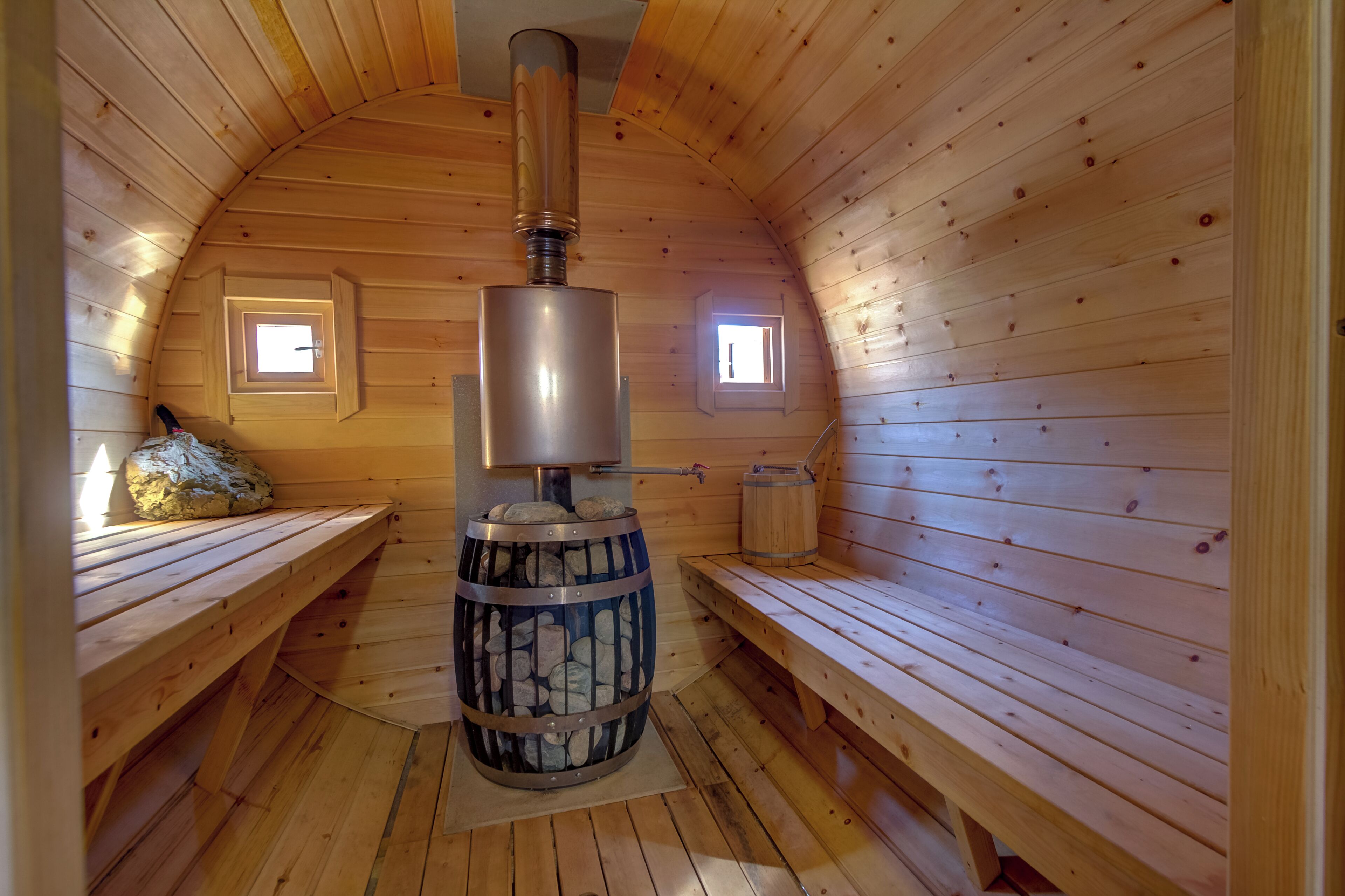 Una sauna de madera con bancos y un calentador central de piedra.