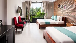 Une chambre d’hôtel moderne, dotée d’un grand lit, d’un bureau avec une chaise et offrant une vue sur la verdure par la fenêtre.