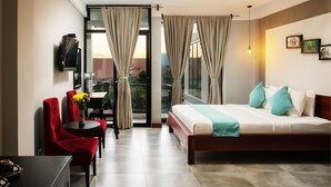 Une chambre d’hôtel avec un lit, un bureau, une chaise et un téléviseur.