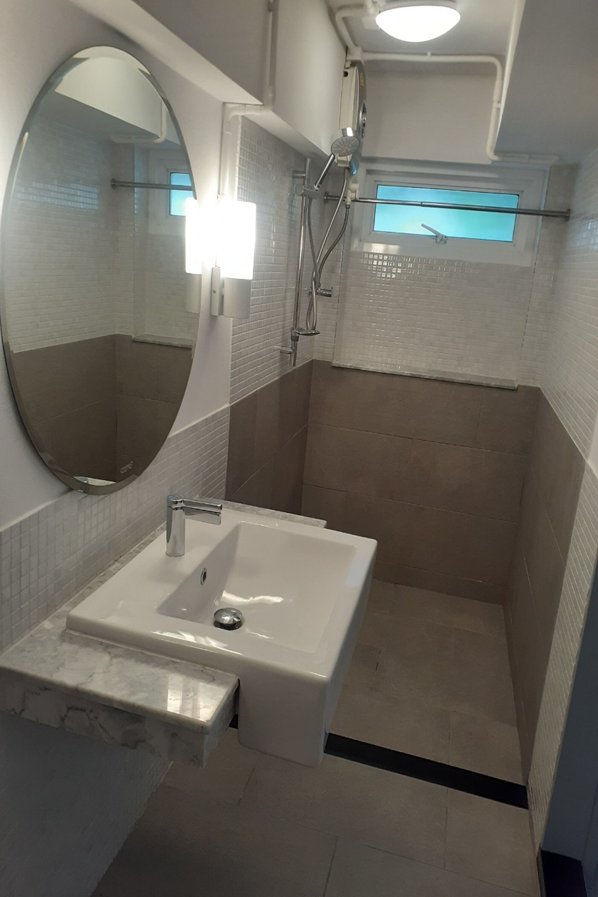 A modern bathroom with a white sink, a large mirror, and a shower area.