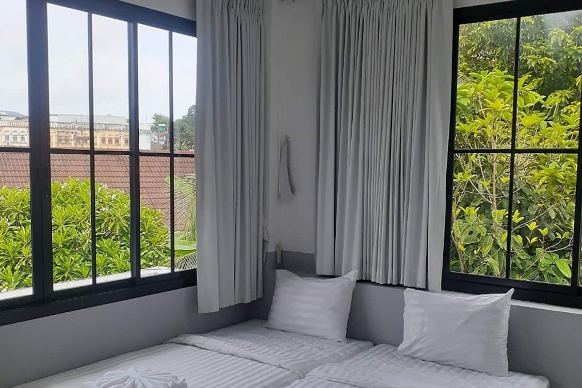 Ein Hotelzimmer mit zwei Betten, großen Fenstern und Vorhängen.