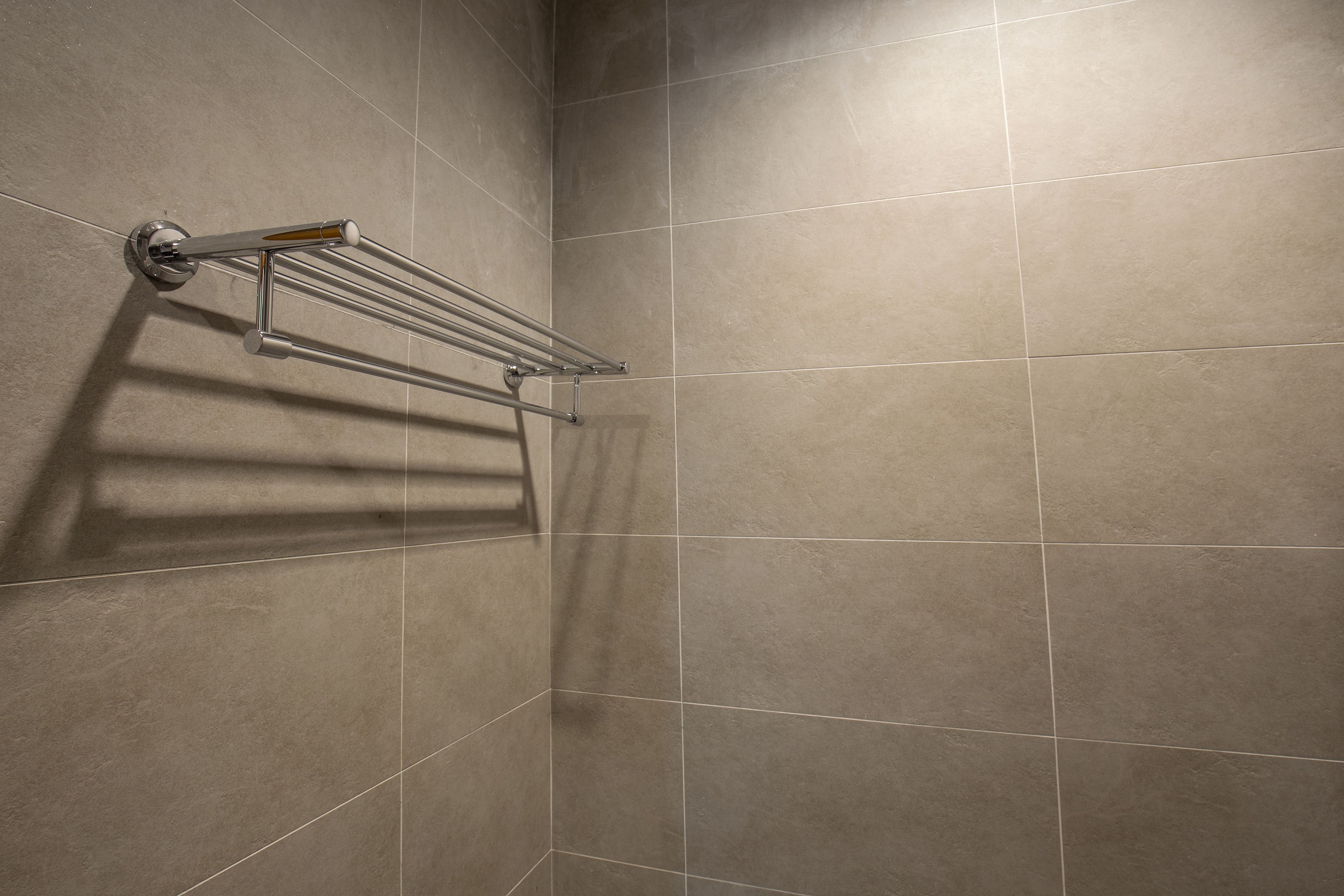 Un baño con un perchero fijado en una pared con azulejos.