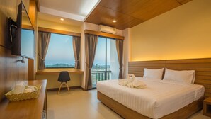 Une chambre d’hôtel avec un grand lit, un bureau avec un panier, une chaise et un téléviseur fixé au mur.