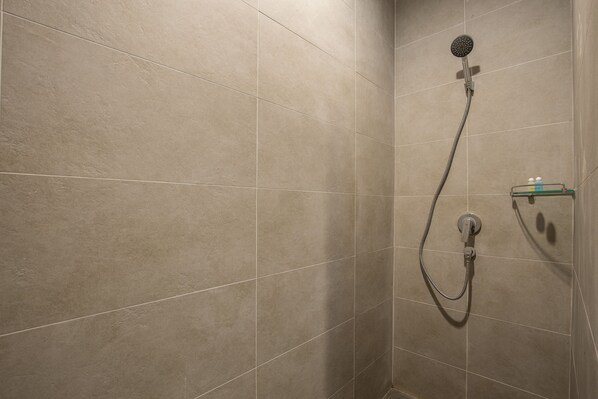 A shower area with beige tiles and a handheld showerhead. - Sann View Hotel (Thoeng)