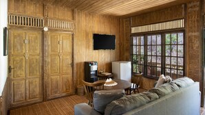 Una habitación con paneles de madera, un sofá, una mesa con un pastel, un dispensador de agua, un refrigerador y un televisor montado en la pared.