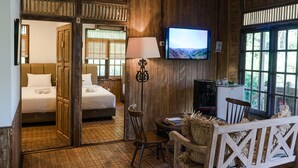 Una habitación de madera con una cama, un televisor y una zona de comedor.