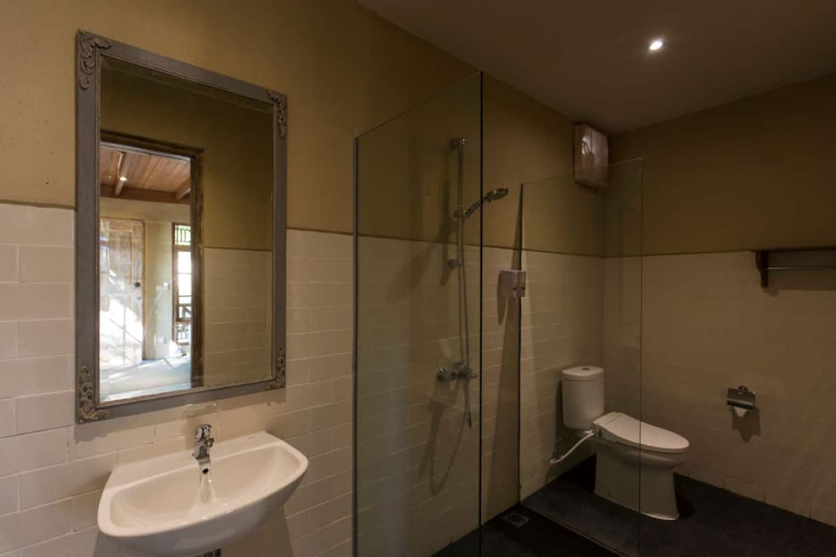 Un baño con ducha de vidrio, lavamanos blanco y un inodoro.