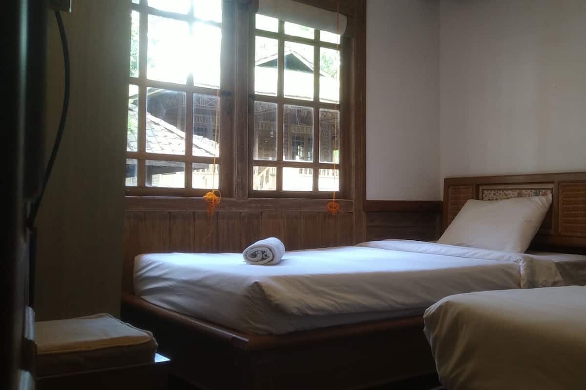 Una habitación con dos camas, una ventana que ofrece vistas a edificios y un cabecero de madera.