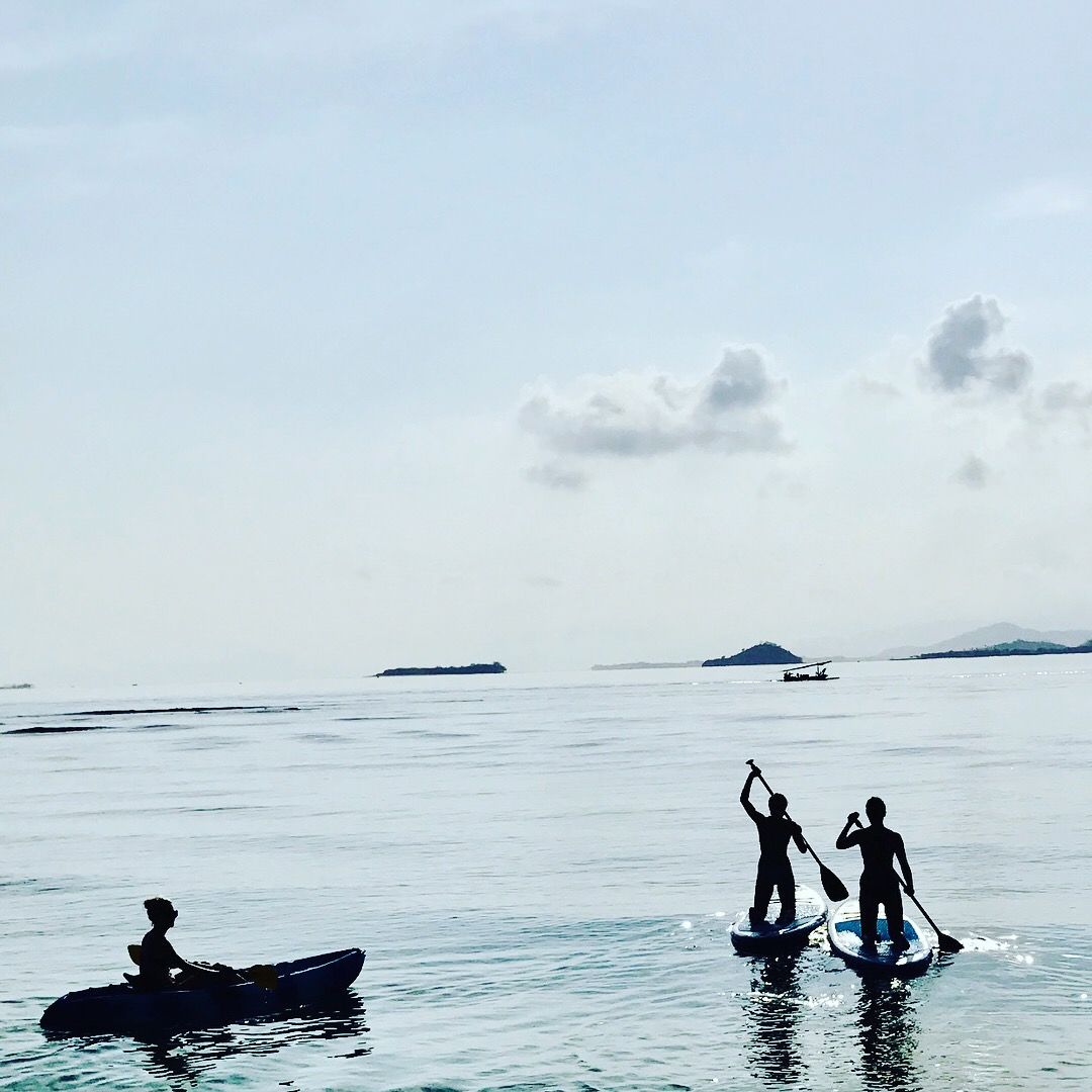 Mare calmo con tre persone su paddleboard e una persona in una piccola barca.