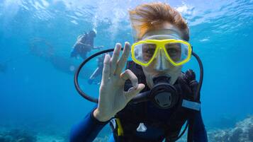 A diver underwater with a scuba mask and fins, surrounded by clear blue water and marine life.