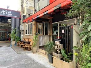 A hostel with a red awning, outdoor seating, and potted plants. - 09 Hostel (Chiang Mai)