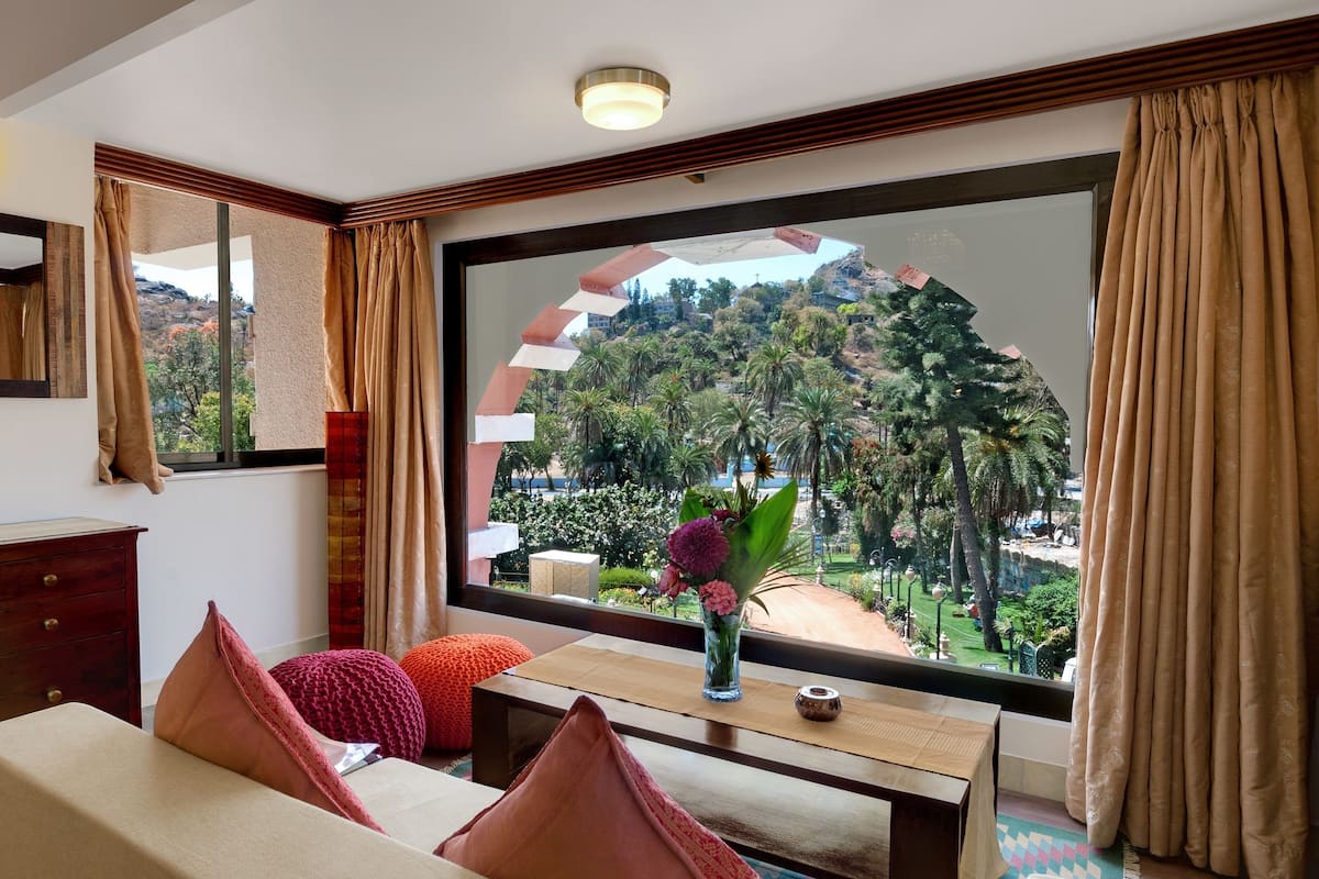 Una habitación moderna con un ventanal grande, un escritorio de madera, un sofá y un jarrón decorativo.