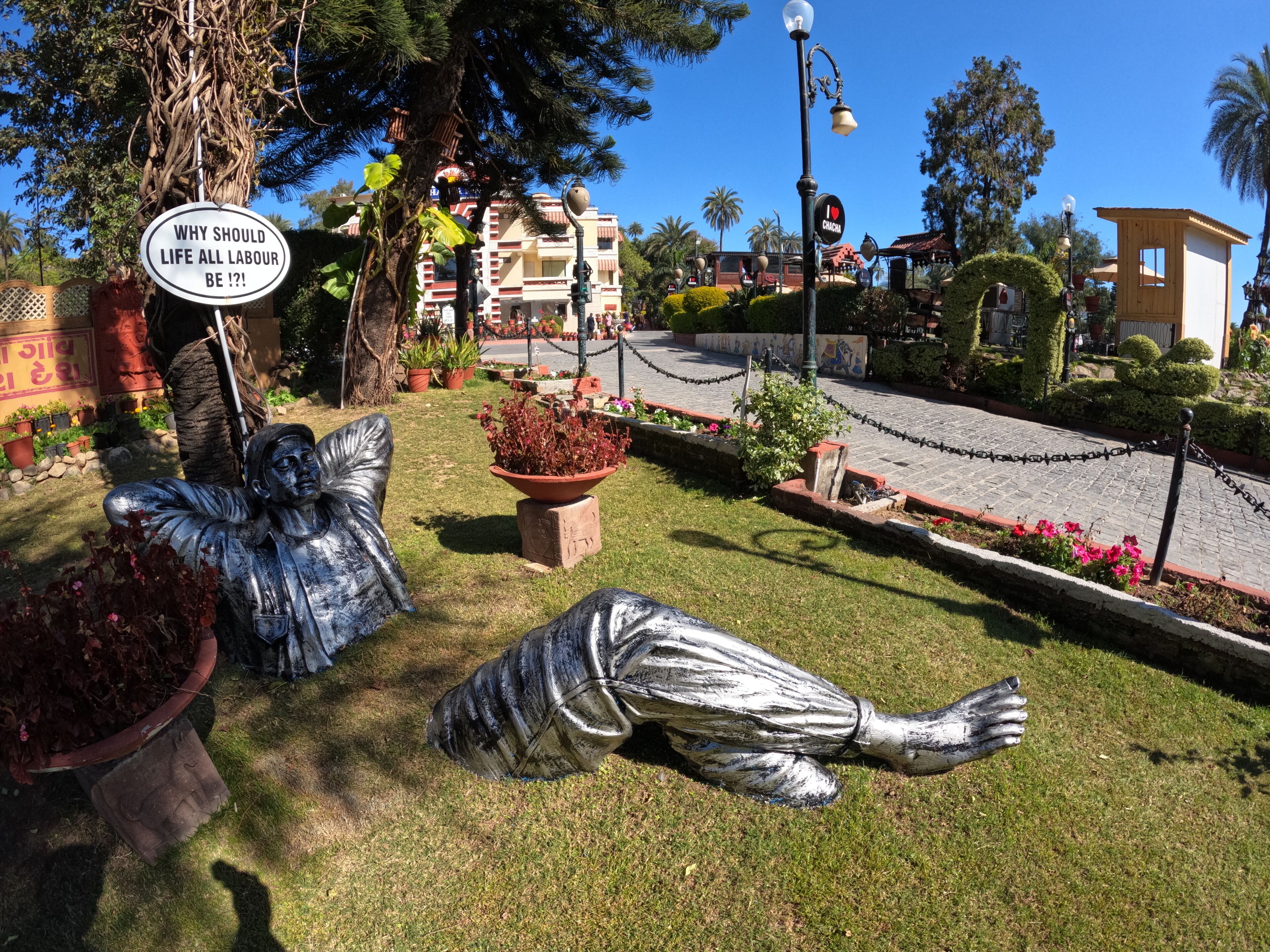 A garden with statues, a sign, and a building in the background.