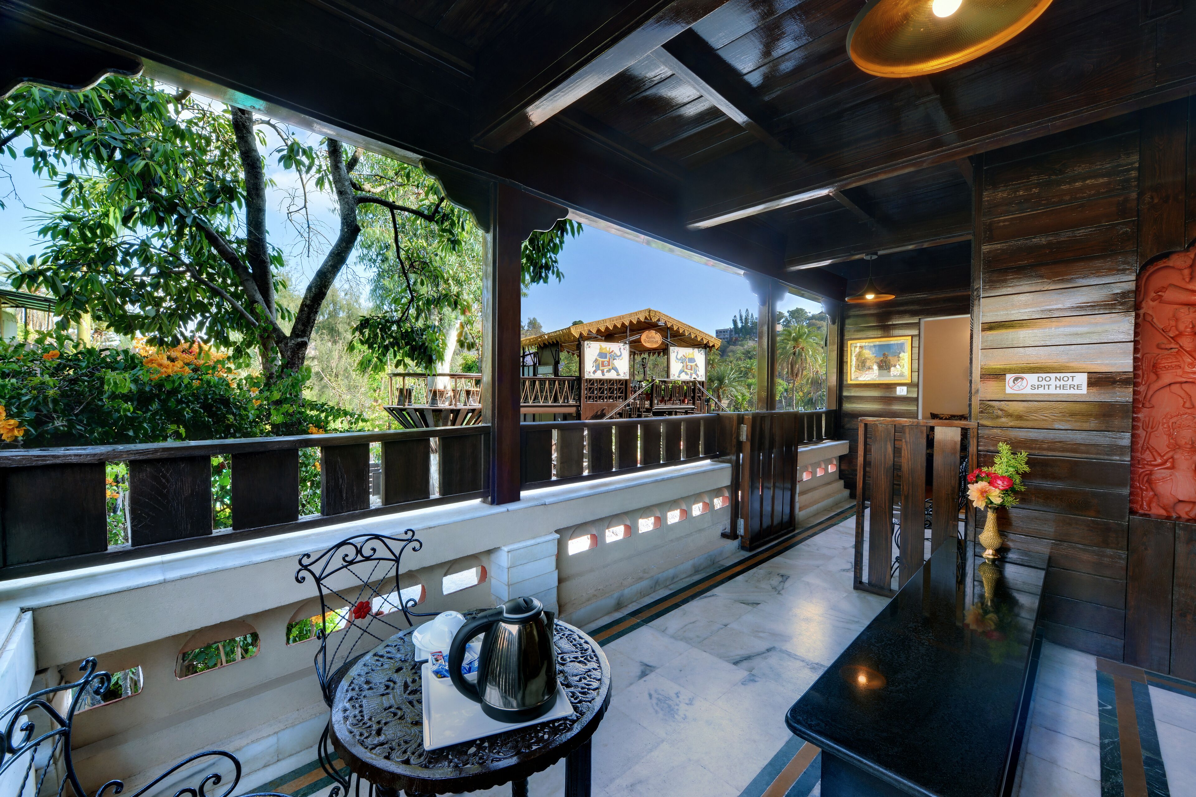 A covered outdoor seating area with a table, chairs, and a view of a traditional building.