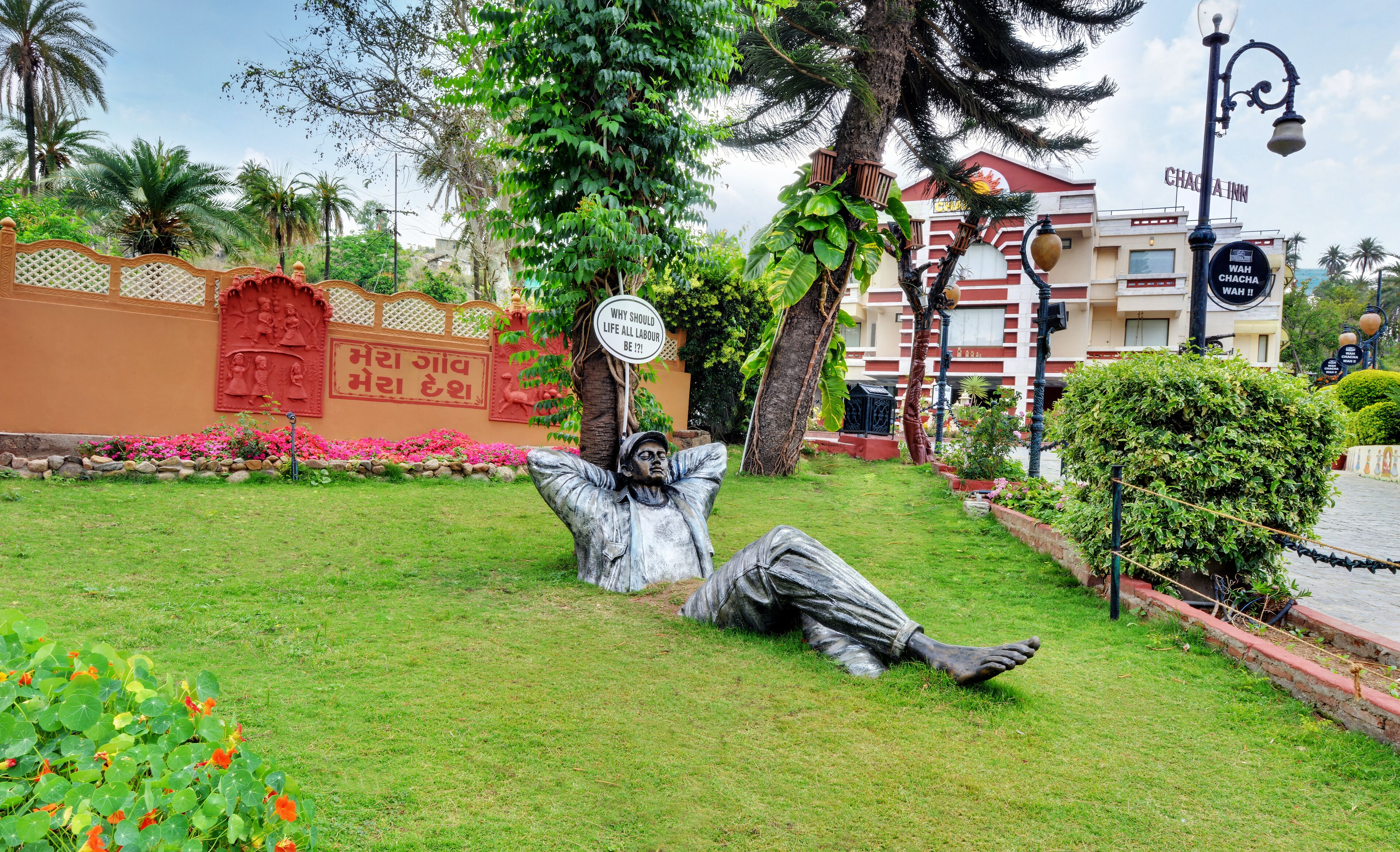 A garden with a statue of a man lying down, a sign with a question, and a building labeled "Chachapurna".