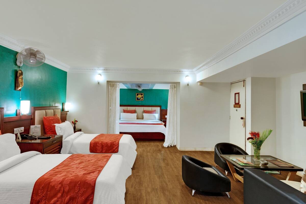 Habitación de hotel con dos camas, un escritorio, una silla, un televisor y un ventilador de techo.