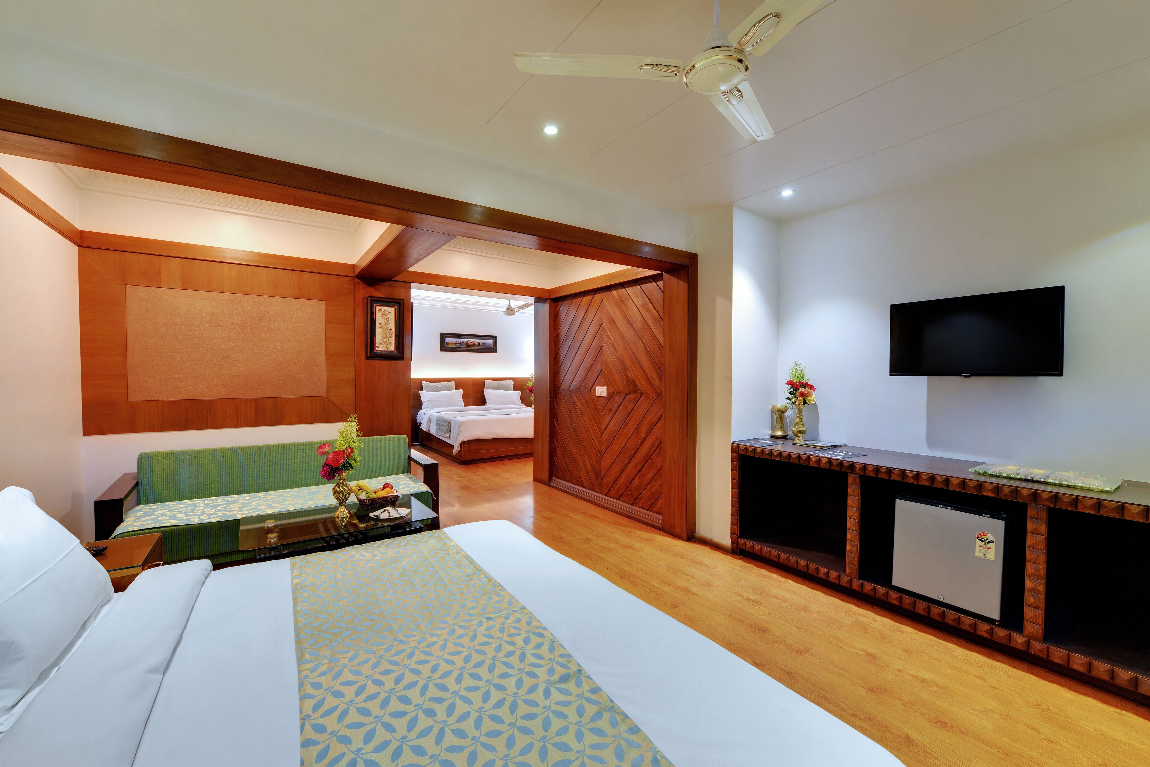 Habitación de hotel con cama, escritorio, televisión y panel de pared de madera.