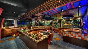 Zona de bar moderna con mostrador curvo, asientos y techo decorativo.
