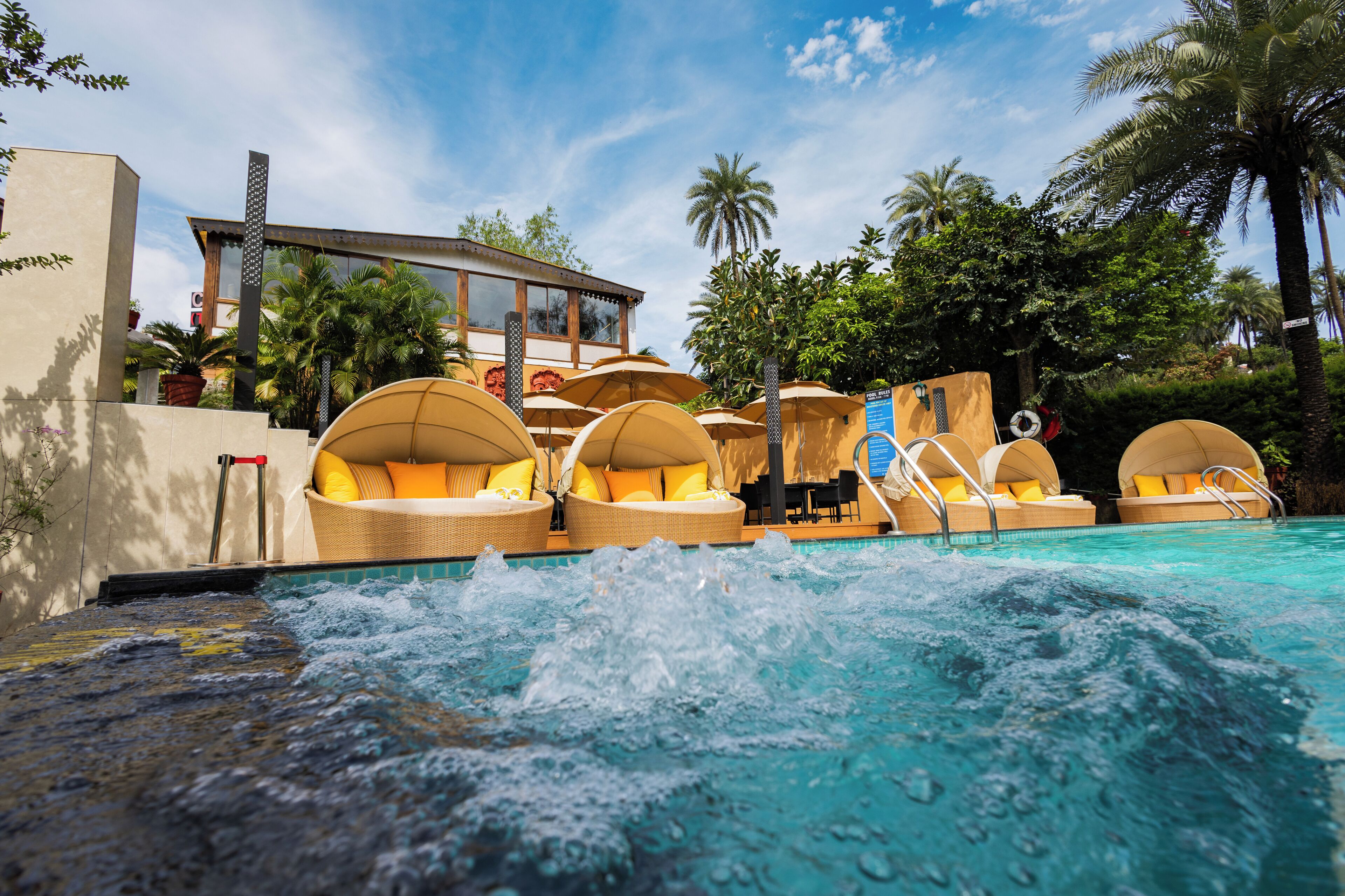 A pool area with multiple sun loungers and a building in the background.