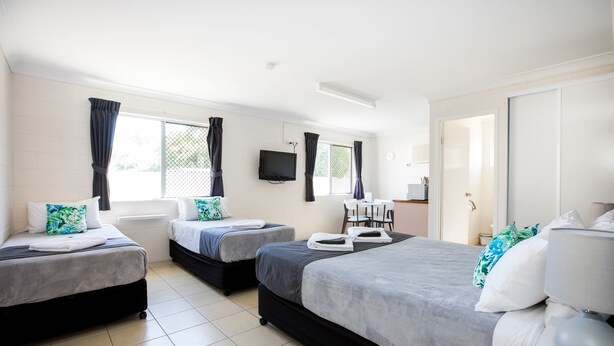 Une chambre d’hôtel avec trois lits, un téléviseur à écran plat et un placard à portes coulissantes.