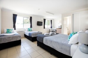 A hotel room with three beds, a flat-screen TV, and a sliding door closet. - Banjo Paterson Motor Inn (Rosslea)