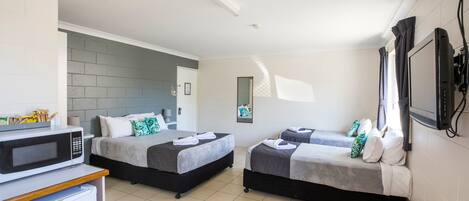 A hotel room with two beds, a microwave, a refrigerator, and a television.