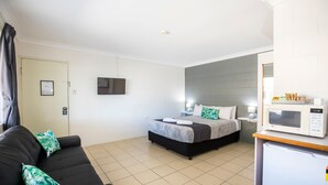Une chambre d’hôtel équipée d’un lit, d’un canapé, d’une télévision, d’un four à micro-ondes et d’un réfrigérateur.