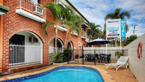 Un motel doté d’une piscine, d’un espace extérieur aménagé et d’une enseigne publicitaire pour un établissement proposant des chambres et un restaurant.