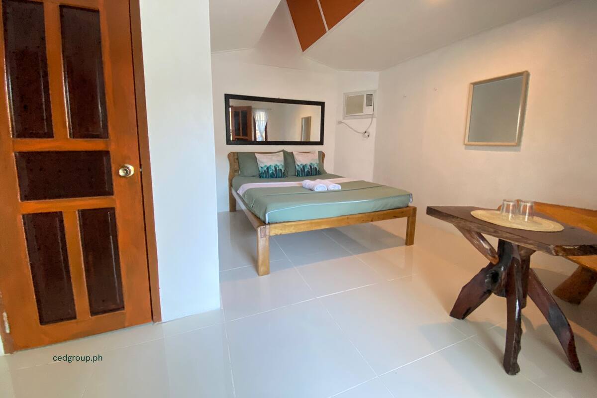 Ein Schlafzimmer mit einem Bett, einer hölzernen Bank, einem kleinen Tisch und einer Tür.